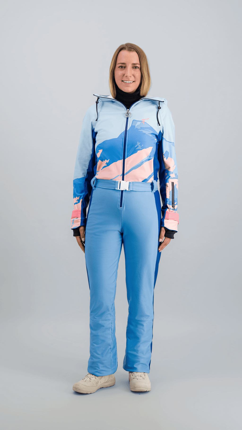 Modèle en combinaison de ski Fuzance bleu glacier, prête pour les pistes, avec détails techniques modernes.