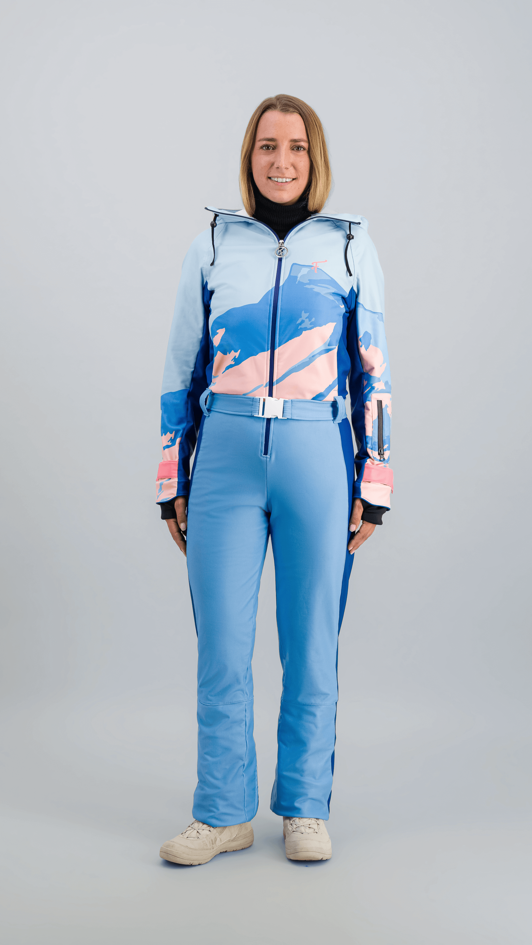 Modèle en combinaison de ski Fuzance bleu glacier, prête pour les pistes, avec détails techniques modernes.