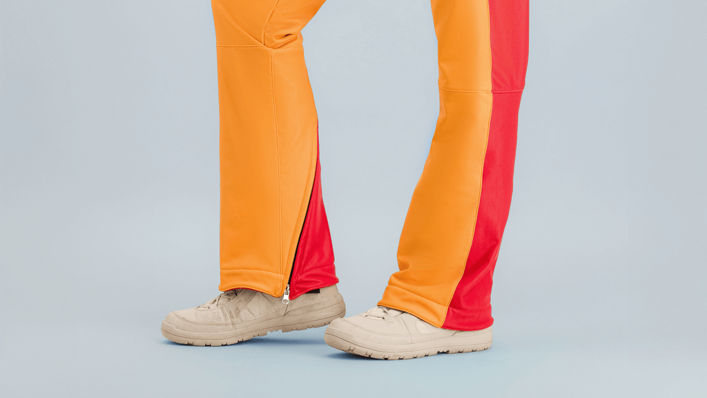 Combinaison de ski Hélios avec des couleurs rouge-orange, inspirée des années 80, idéale pour les pistes.