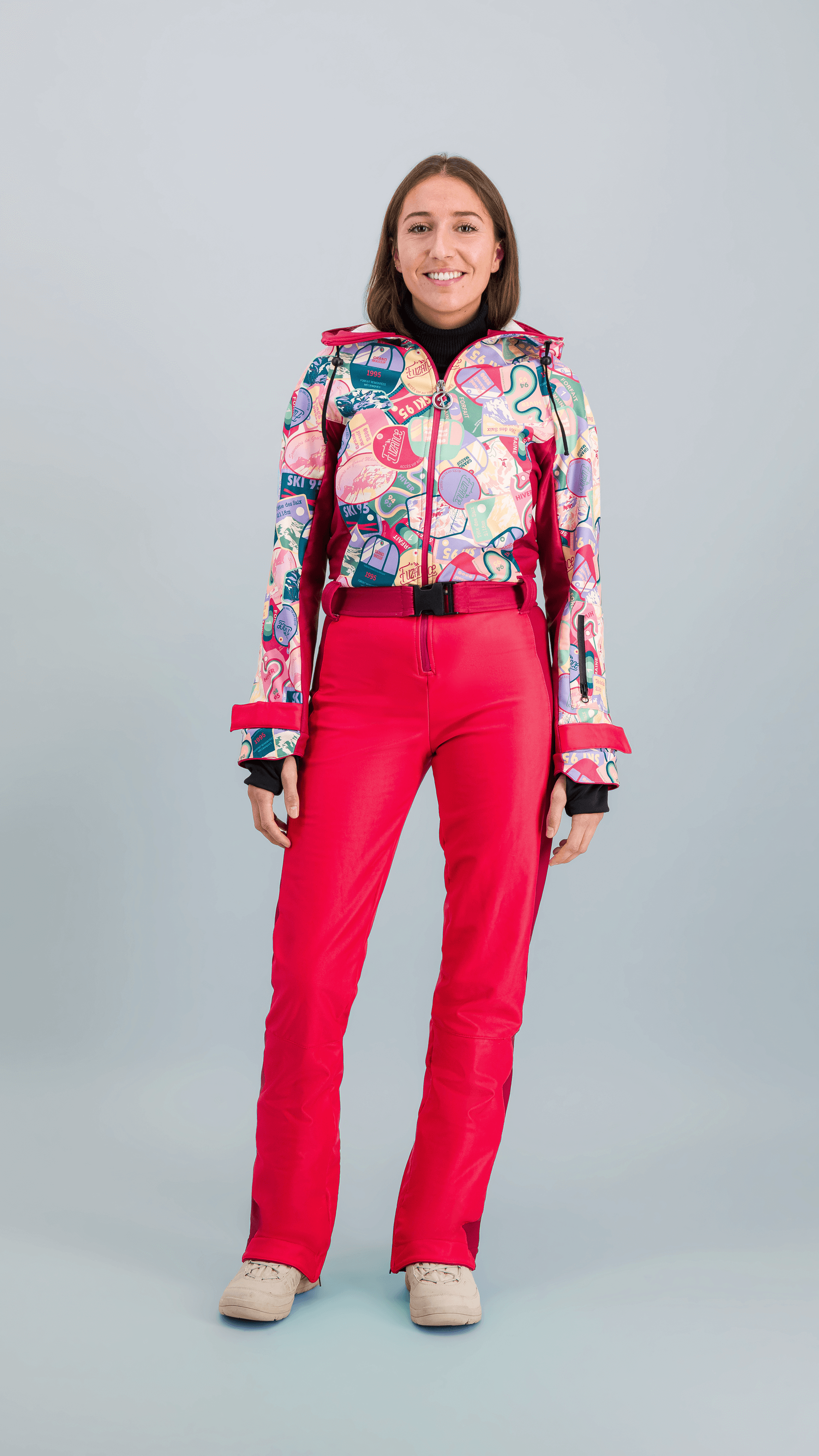 Femme portant une combinaison de ski Rouge Forfait avec motifs rétro et couleurs vives.
