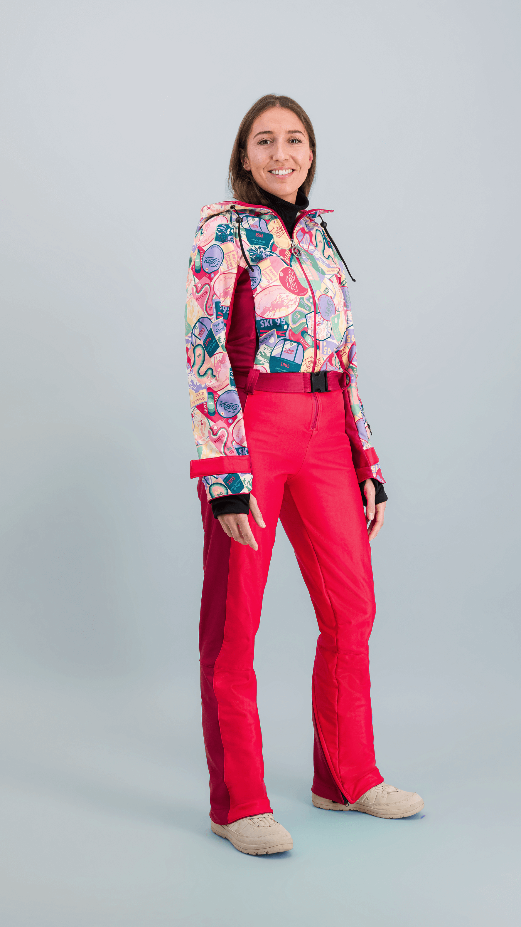 femme portant une combinaison de ski couleur rouge et multicolore, style rétro, prête pour skier.