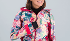 Femme souriante portant une combinaison de ski Forfait au design rétro coloré et motifs vintage.
