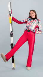 Femme portant une combinaison de ski colorée, posant avec des skis, évoquant le style nostalgique du ski rétro.