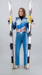 Femme portant une combinaison de ski bleue Fuzance sur fond clair, inspirée du style rétro des années 80.